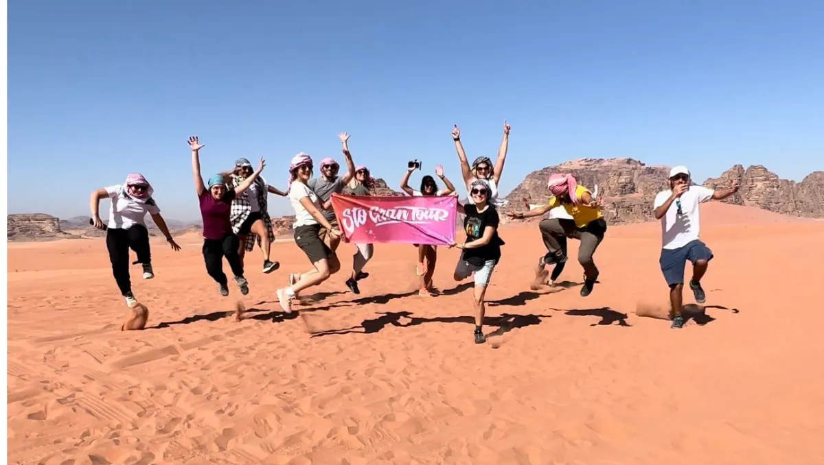 The group jumping with the Sto Gran Tour banner on the red sand of Wadi Rum