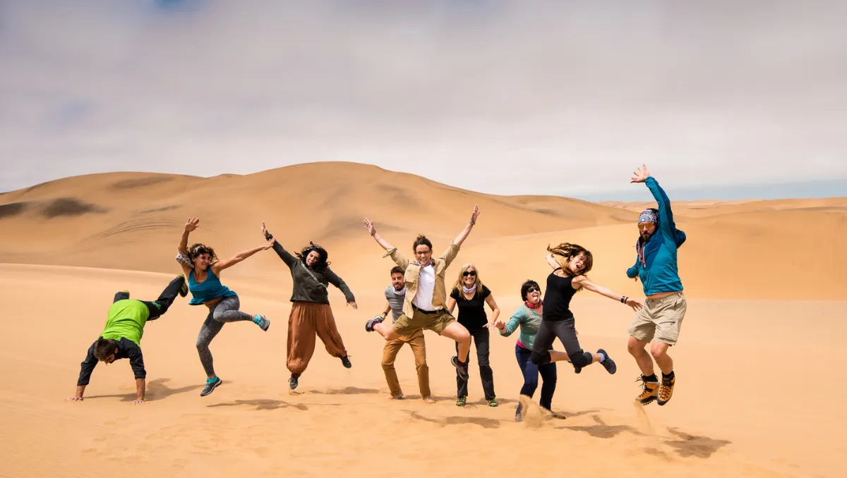 The group jumping and doing cartwheels on the desert sand dunes